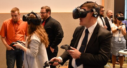 IMAGE: KING GEORGE, Va. (May 22, 2019) – Three attendees engage in a virtual reality visualization of Navy ships – inside and out – at the first annual Modeling and Simulation Summit sponsored by the Naval Surface Warfare Center Dahlgren Division. Two engineers fly around the topside of Navy ships via virtual reality while a third explores the interior of an amphibious transport dock ship’s pilot house. 
The event – held at the University of Mary Washington Dahlgren campus – focused on modeling and simulation capabilities in areas such as model-based systems engineering, mission engineering and analysis, theater and force level modeling, computational physics, optimization, virtual reality and 3D scanning.  (U.S. Navy Photo/Released)