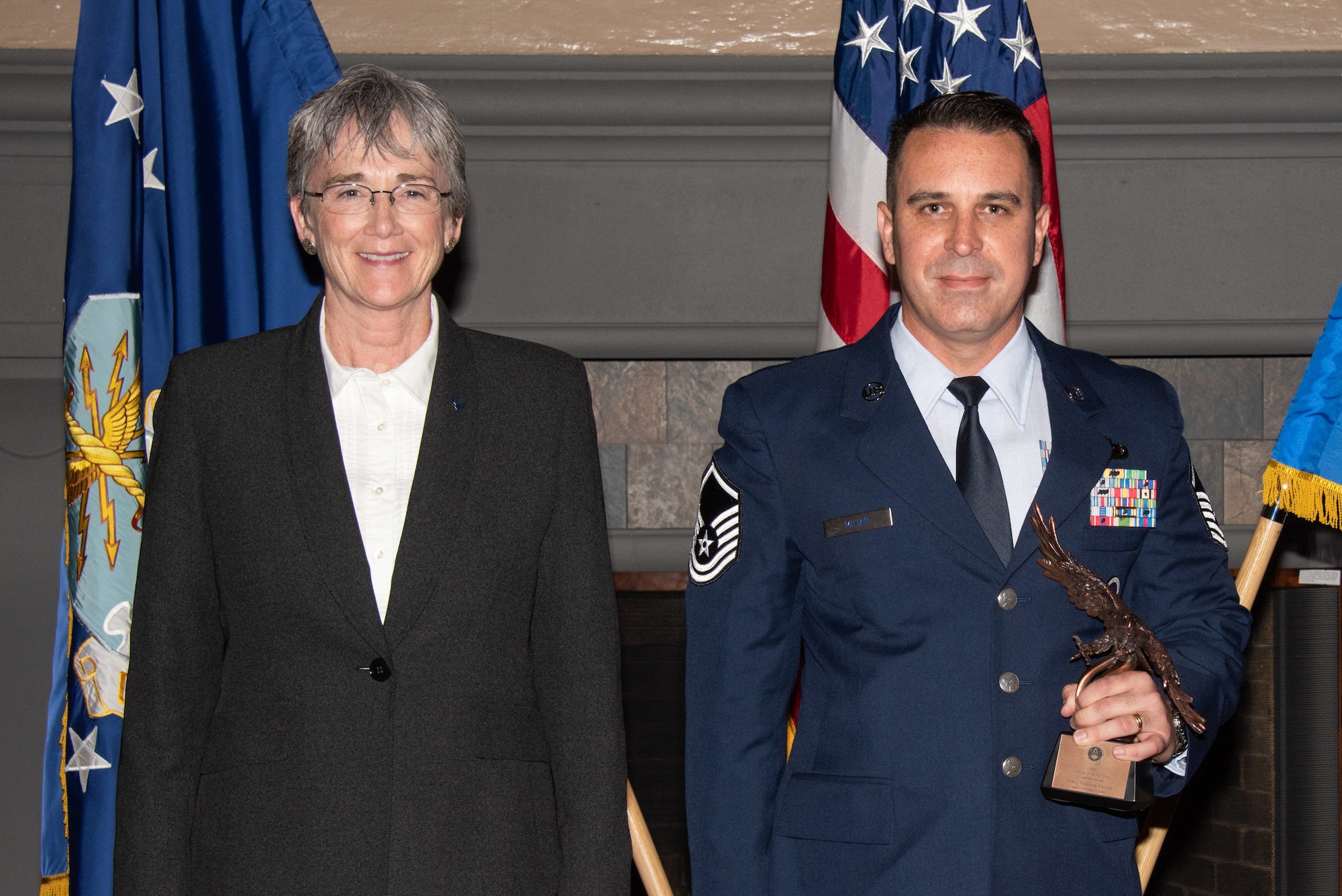 Secretary of the Air Force Heather Wilson, left, presents Master Sgt. Roldan Milian, Officer Training School military training instructor superintendent, right, with the 2019 Secretary of the Air Force Leadership Award May 14, 2019, at Maxwell Air Force Base, Alabama. Milian led a ten-person MTI corps, supporting the training and commissioning of 3,400 new officers, totaling 54 percent of the Air Force’s officer accessions. He also earned the flight room evaluator certification typically reserved for the officer corps, supporting 240 officer and enlisted evaluations for staff. Additionally, he worked with the Air University commander to fill a critical resource gap, accelerating the arrival of all future MTIs to duty at OTS by 90 days. His efforts earned him the Holm Center’s Senior Non-Commissioned Officer of the Year and the 2018 Lance P. Sijan nomination to AU.