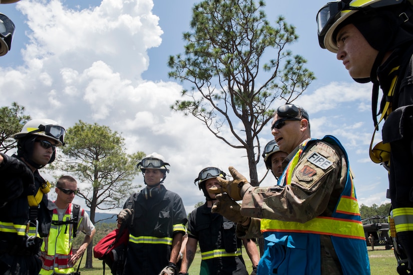 Firefighters from the 612th Air Base Squadron discuss the situation and plan to retrieve a simulated patient during a search and rescue exercise, May 21, 2019, in Comayagua, Honduras. Members from various units on Joint Task Force – Bravo participated in the exercise that simulated a HH-60 Blackhawk crashed during a routine flight carrying personnel. The exercise practiced notification, recall, search and rescue, on-scene medical care, recovery of personnel from low and high angle austere terrain, and medical care once the injured returned to base. (U.S. Air Force photo by Staff Sgt. Eric Summers Jr.)