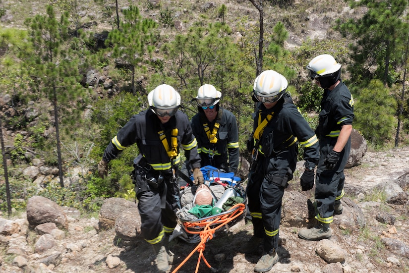 A group of Airmen from the 612th Air Base Squadron haul a simulated patient up a hill during a search and rescue exercise, May 21, 2019, in Comayagua, Honduras. Members from various units on Joint Task Force – Bravo participated in the exercise that simulated a HH-60 Blackhawk crashed during a routine flight carrying personnel. The exercise practiced notification, recall, search and rescue, on-scene medical care, recovery of personnel from low and high angle austere terrain, and medical care once the injured returned to base. (U.S. Air Force photo by Staff Sgt. Eric Summers Jr.)