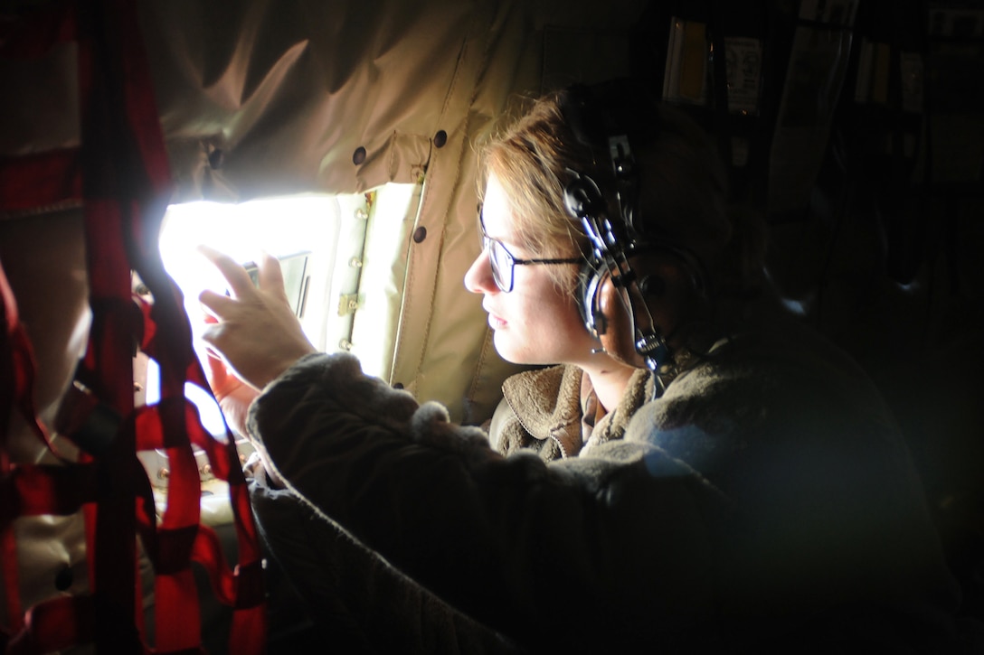 An airman looks out a window of an aircraft.