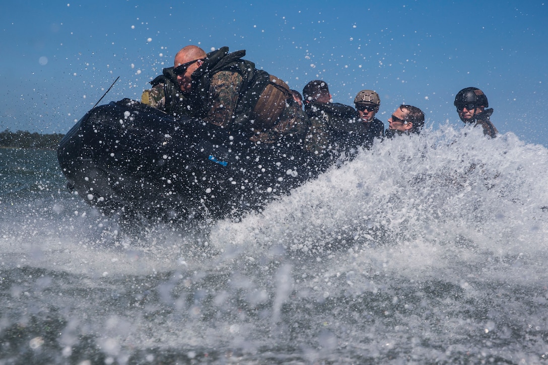 Marines ride an inflatable craft that makes a splash as it cuts through water.