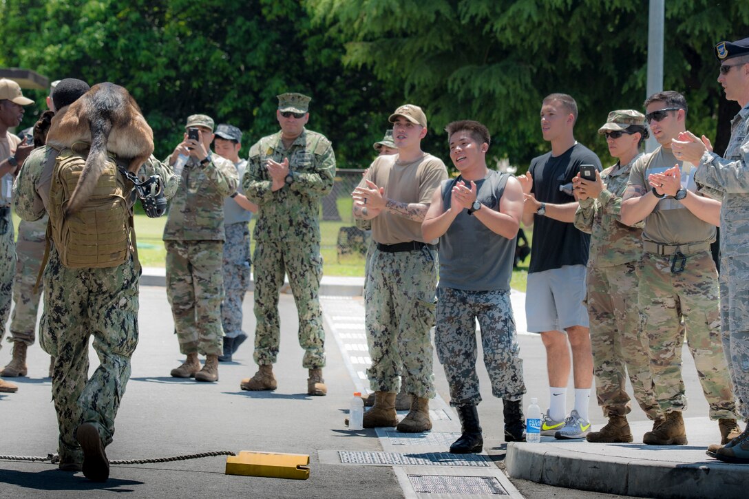Master-at-Arms 2nd Class Howard Norris, Commander Fleet Activities Yokosuka Security Department military working dog handler and his military working dog, Ttibor, cross the finish line during Yokota's 2019 National Police Week Iron Dog competition, May 24, 2019, at Yokota Air Base, Japan.