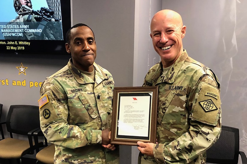 Maj. Gen. David C. Coburn, U.S. Army Financial Management Command commanding general, right, presents Lt. Col. Andre Brown, USAFMCOM assistant chief of staff for operations, with a letter congratulating him on his selection for promotion to the rank of colonel at the Maj. Gen. Emmet J. Bean Federal Center in Indianapolis May 21, 2019. U.S. military colonels rank above a lieutenant colonel and below a brigadier general.