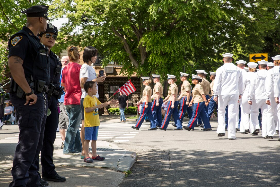 A group of New York natives watch as a formation of Marines, sailors, and Coast Guard members, march in a Memorial Day parade as part of Fleet Week New York (FWNY), in Queens, N.Y., May 26, 2019. FWNY is an opportunity for the citizens of New York City and the surrounding tristate area to come together with the nation’s sea services through community engagement to gain a better understanding of how the sea services support the national defense of the United States. (U.S. Marine Corps photo by Cpl. Tojyea G. Matally)