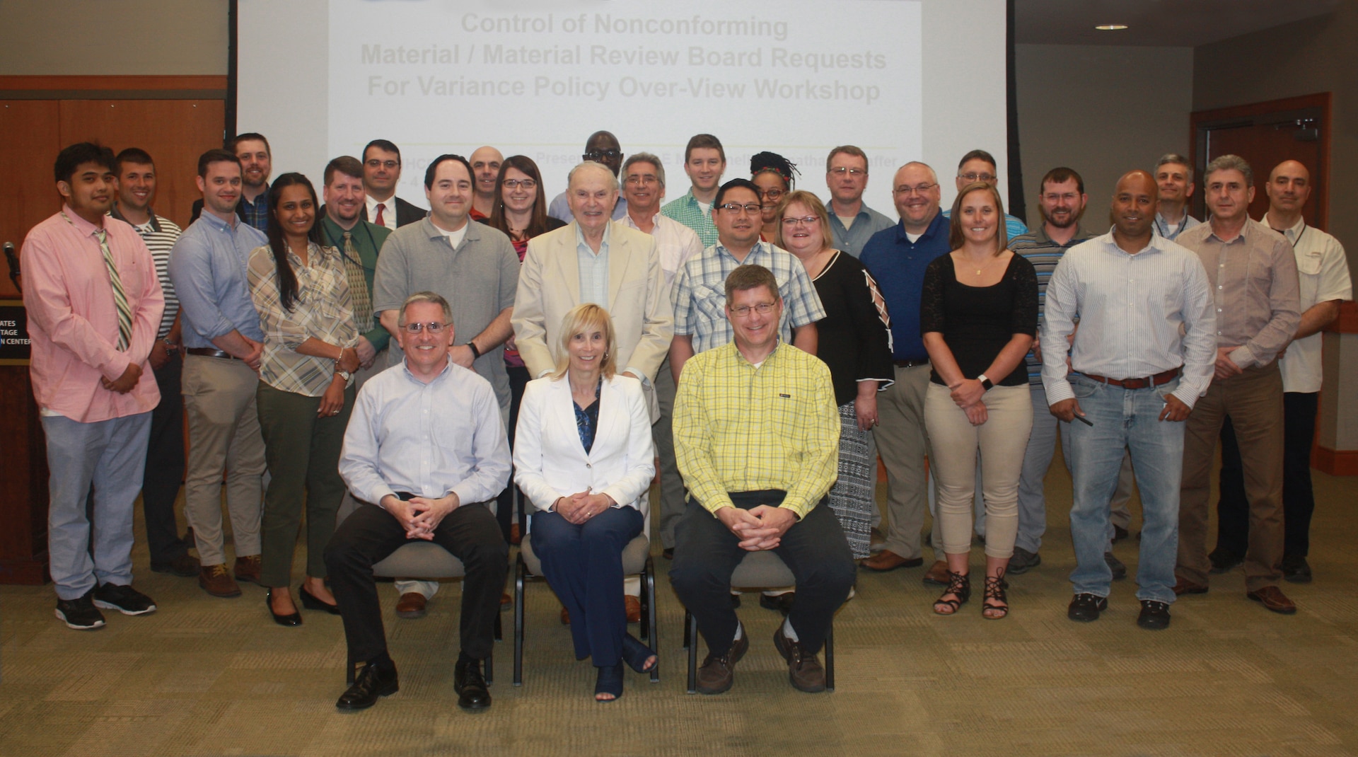 Large group of people pose for a photo in a conference room.