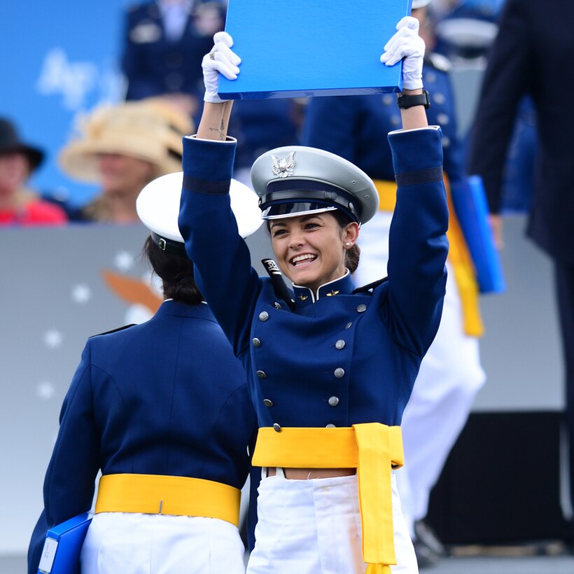 A graduate of the U.S. Air Force Academy holds up a diploma.