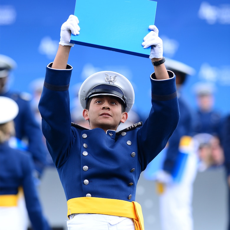 A graduate of the U.S. Air Force Academy holds up a diploma.