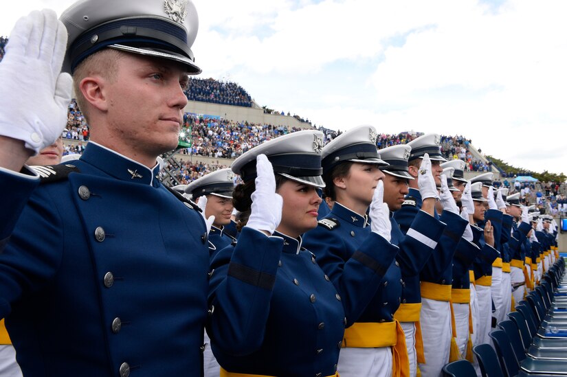 Cadets stand and salute during graduation.