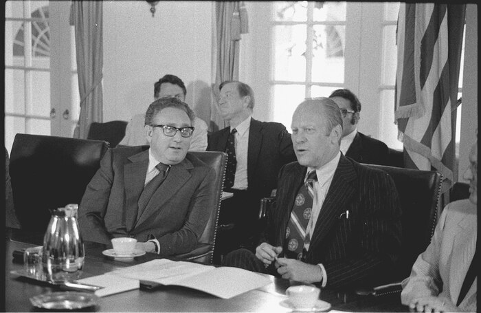 Secretary of State Henry Kissinger and President Gerald Ford seated at a conference table in the White House, during a cabinet meeting