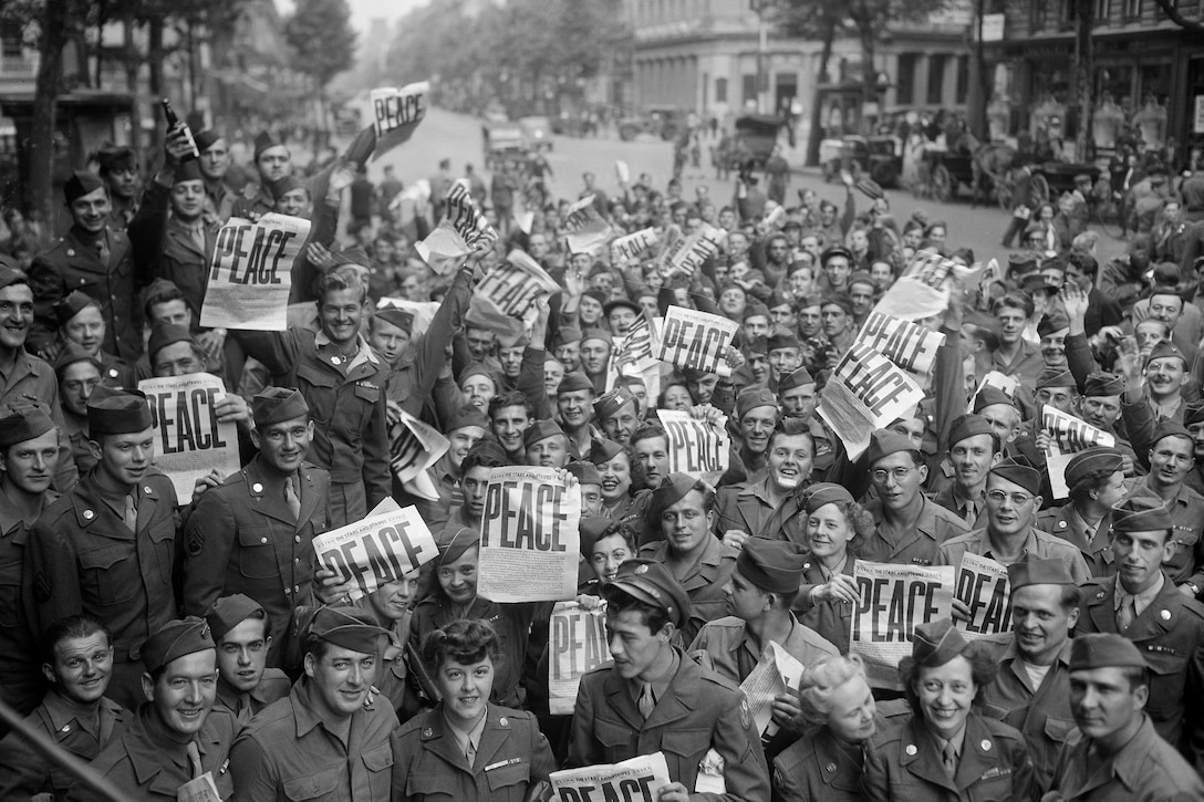 A crowd smiles for a photo and holds up peace signs.