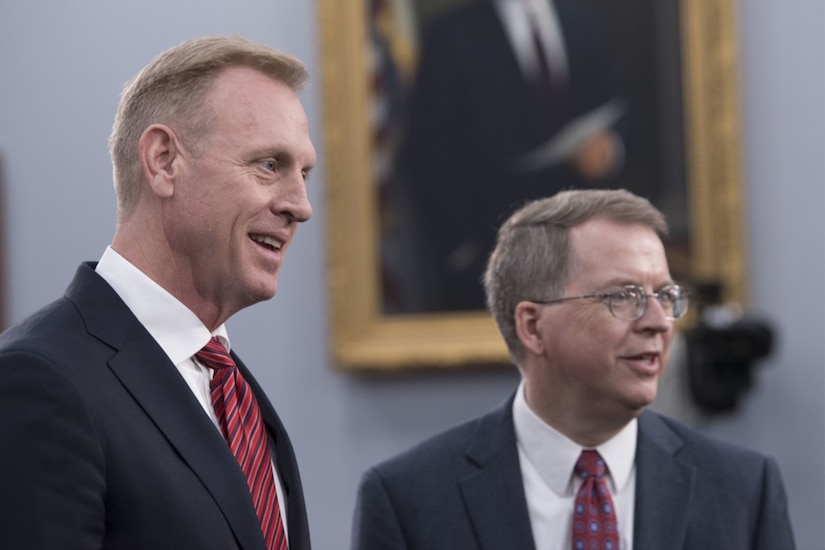 Men in suits talk to people out of frame.