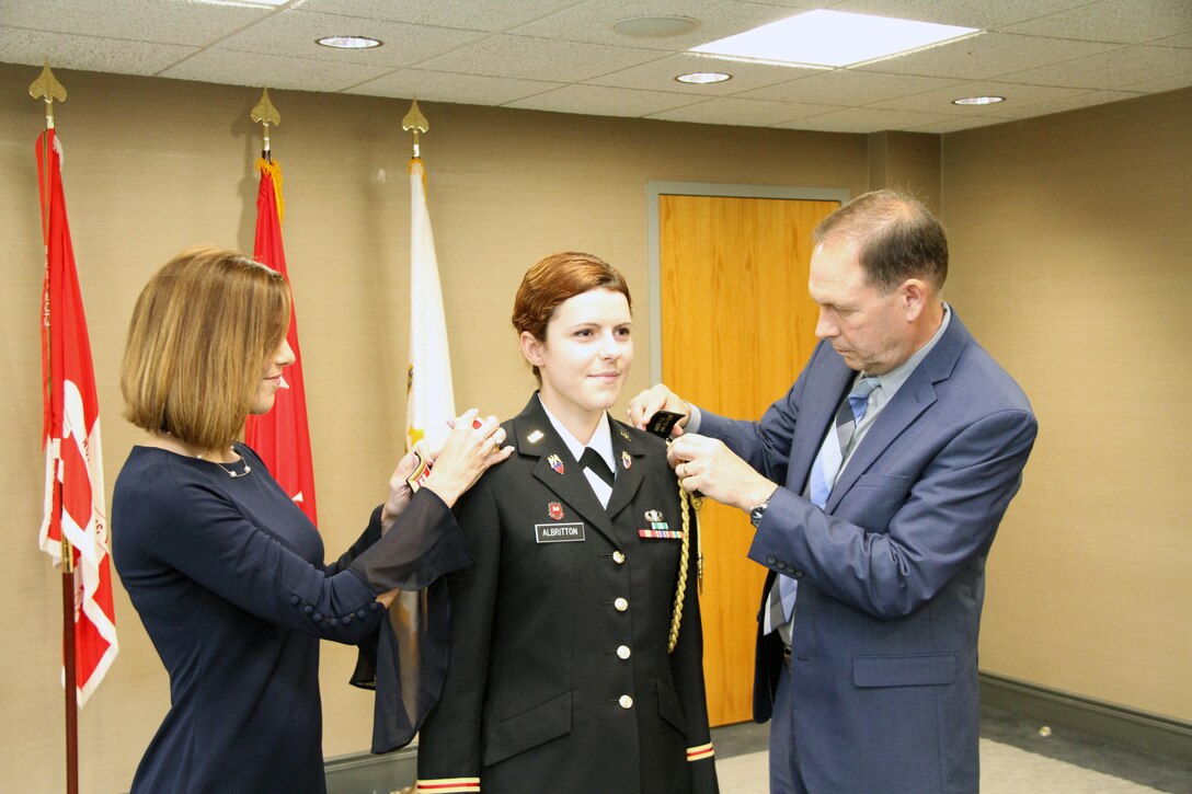 Capt. Shirley Albritton's parents Frankie and Angela replace her first lieutenant shoulder boards with her new rank at a promotion ceremony at Fort Hamilton on May 30, 2019.