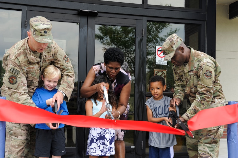 Col. Terrence Adams, right, 628th Air Base Wing commander, Lt. Col. William Parker, left, 628th Force Support Squadron Commander, and Vivian Gadson, 628th FSS flight chief of fleet and family services, participate in a ribbon cutting ceremony with children enrolled in the child development center May 31, 2019, at the Joint Base Charleston Air Base, S.C.