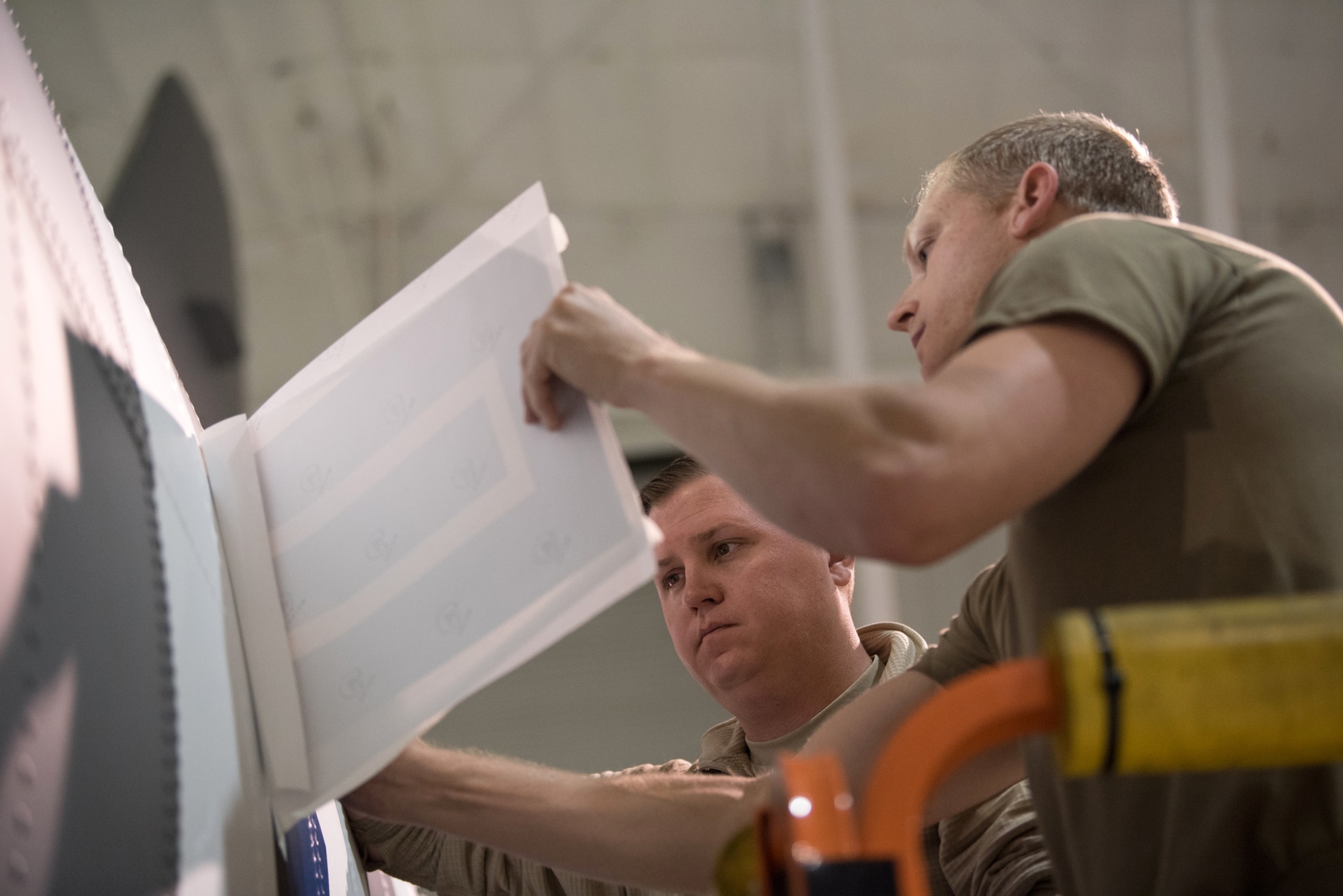 Tech. Sgt. Derek Clow (right), 123rd Maintenance Squadron structural repair technician, and Tech. Sgt. Tyler Shoffner, 123rd Maintenance Squadron metals technician, apply an Air Force roundel decal to a 123rd Airlift Wing C-130 Hercules at the Kentucky Air National Guard Base in Louisville, Ky., May 15, 2019. The C-130 will fly in the 75th anniversary of D-Day over Normandy, France, in June. (U.S. Air National Guard photo by Phil Speck)