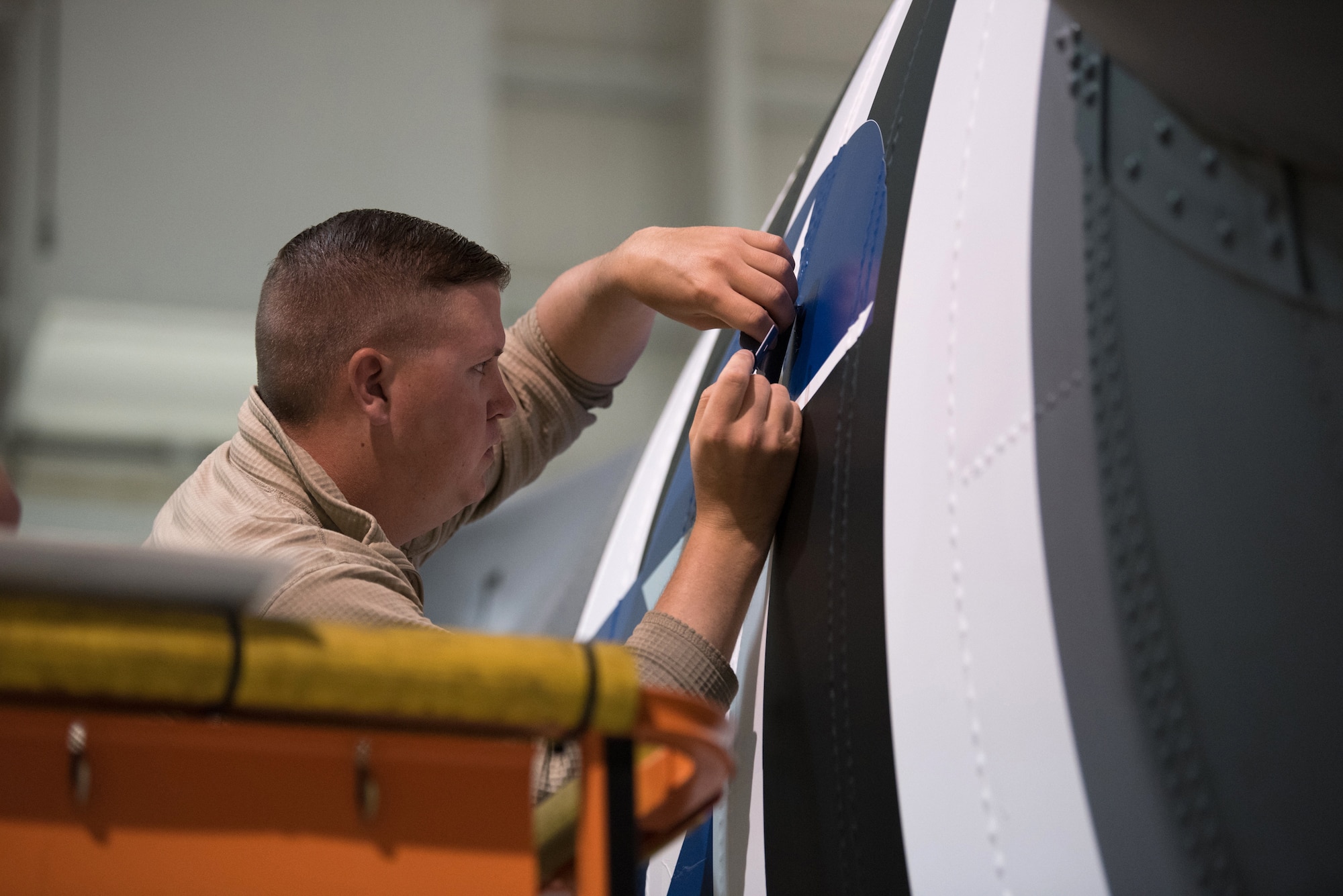 Tech. Sgt. Tyler Shoffner, 123rd Maintenance Squadron metals technician, applies an Air Force roundel decal to a 123rd Airlift Wing C-130 Hercules at the Kentucky Air National Guard Base in Louisville, Ky., May 15, 2019. The C-130 will fly in the 75th anniversary of D-Day over Normandy, France, in June. (U.S. Air National Guard photo by Phil Speck)