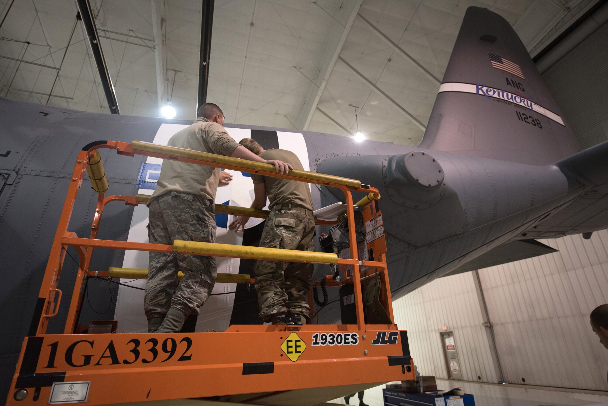 Tech. Sgt. Derek Clow, 123rd Maintenance Squadron structural repair technician, and Tech. Sgt. Tyler Shoffner, 123rd Maintenance Squadron metals technician, apply an Air Force roundel decal to a 123rd Airlift Wing C-130 Hercules at the Kentucky Air National Guard Base in Louisville, Ky., May 15, 2019. The C-130 will fly in the 75th anniversary of D-Day over Normandy, France, in June. (U.S. Air National Guard photo by Phil Speck)