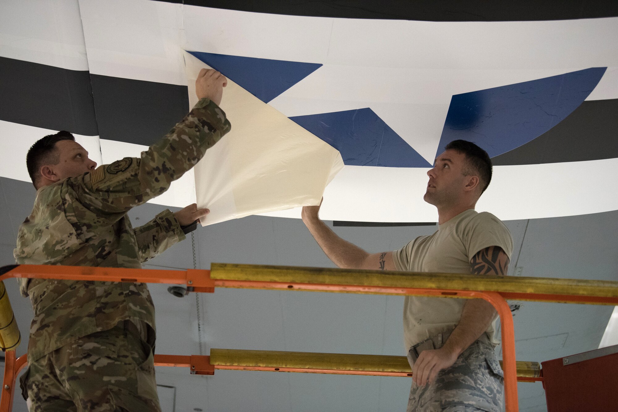 Master Sgt. Jonathan Stanley (left), 123rd Maintenance Squadron non-destructive inspection noncommissioned-officer-in-charge, and Senior Airman Hans Larson, 123rd Maintenance Squadron aircraft structural maintenance technician, apply an Air Force roundel decal to a 123rd Airlift Wing C-130 Hercules at the Kentucky Air National Guard Base in Louisville, Ky., May 15, 2019. The C-130 will fly in the 75th anniversary of D-Day over Normandy, France, in June. (U.S. Air National Guard photo by Phil Speck)