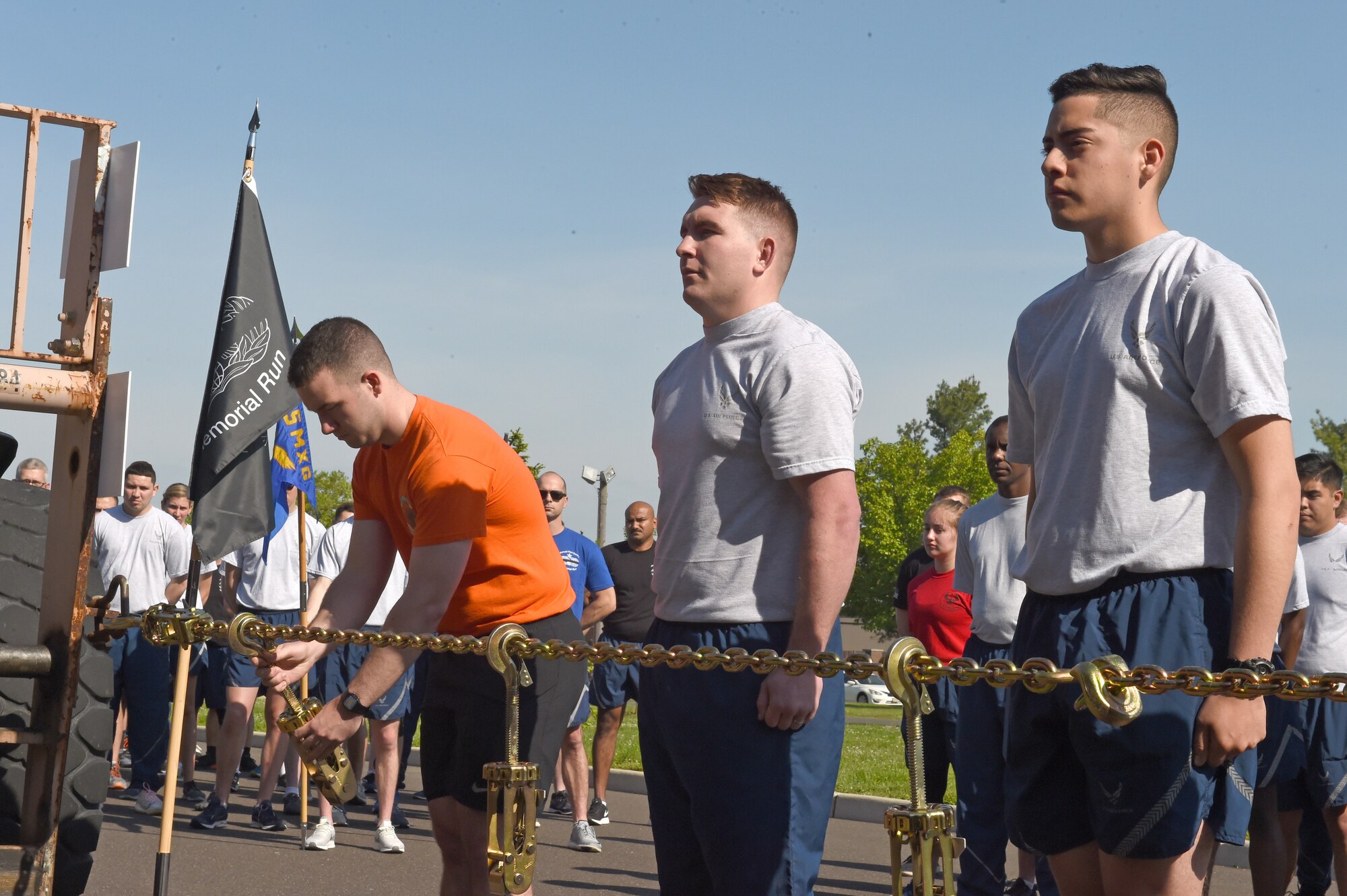 Airmen place devices for each fallen Port Dawg on a chain stretched across two forklifts during the opening ceremony at Joint Base McGuire-Dix-Lakehurst, N.J. May 17, 2019. The Port Dawg Memorial Run honors aerial porters who lost their lives the previous year. (U.S. Air Force photo by Staff Sgt. Sarah Brice)