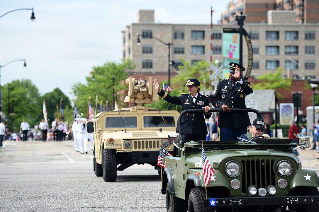 Brig. Gen. Kris Belanger, left, Commanding General, 85th U.S. Army Reserve Support Command, with Command Sgt. Maj. Theodore Dewitt, Command Sergeant Major, 85th USARSC, wave at a crowd during the Village of Arlington Heights Memorial Day parade, Mar. 27, 2019.