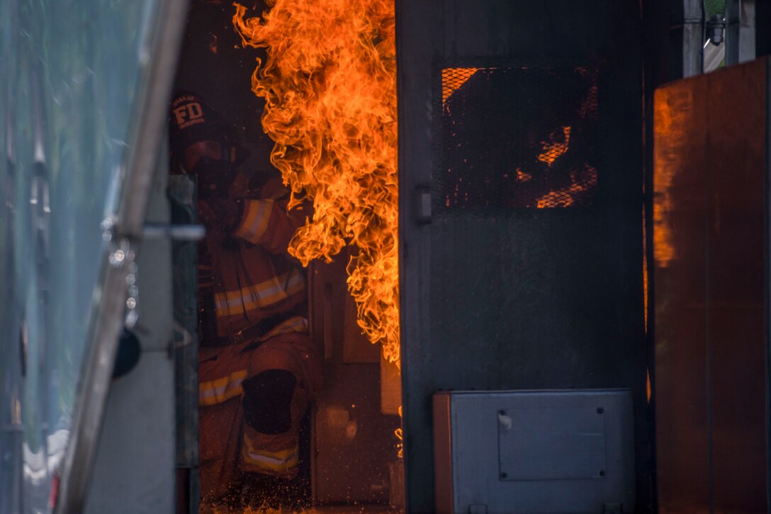 Two firefighters assess a fire in an aircraft while training.