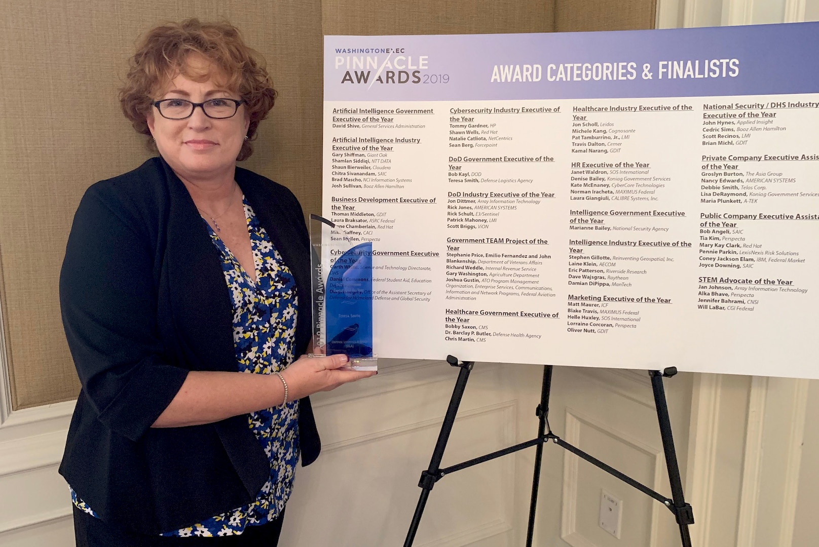 Teresa Smith holds her Department of Defense Government Executive of the Year in front of a sign listing other finalists