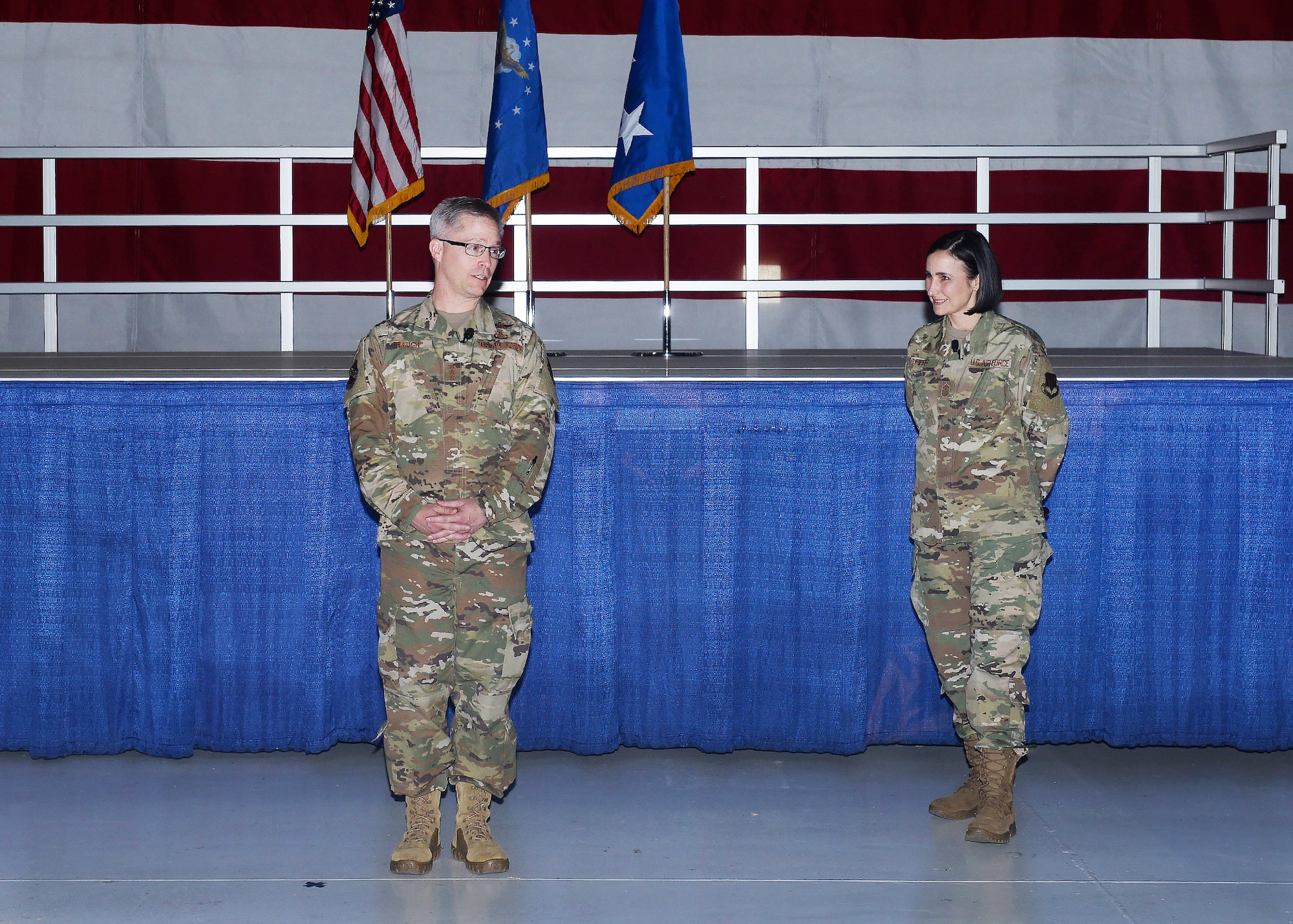 Lt. Gen. Timothy Haugh, 16th Air Force commander, stands in front of a stage with Chief Master Sgt. Summer D. Leifer as they speak to team Offutt members during the 16th Air Force All Call.