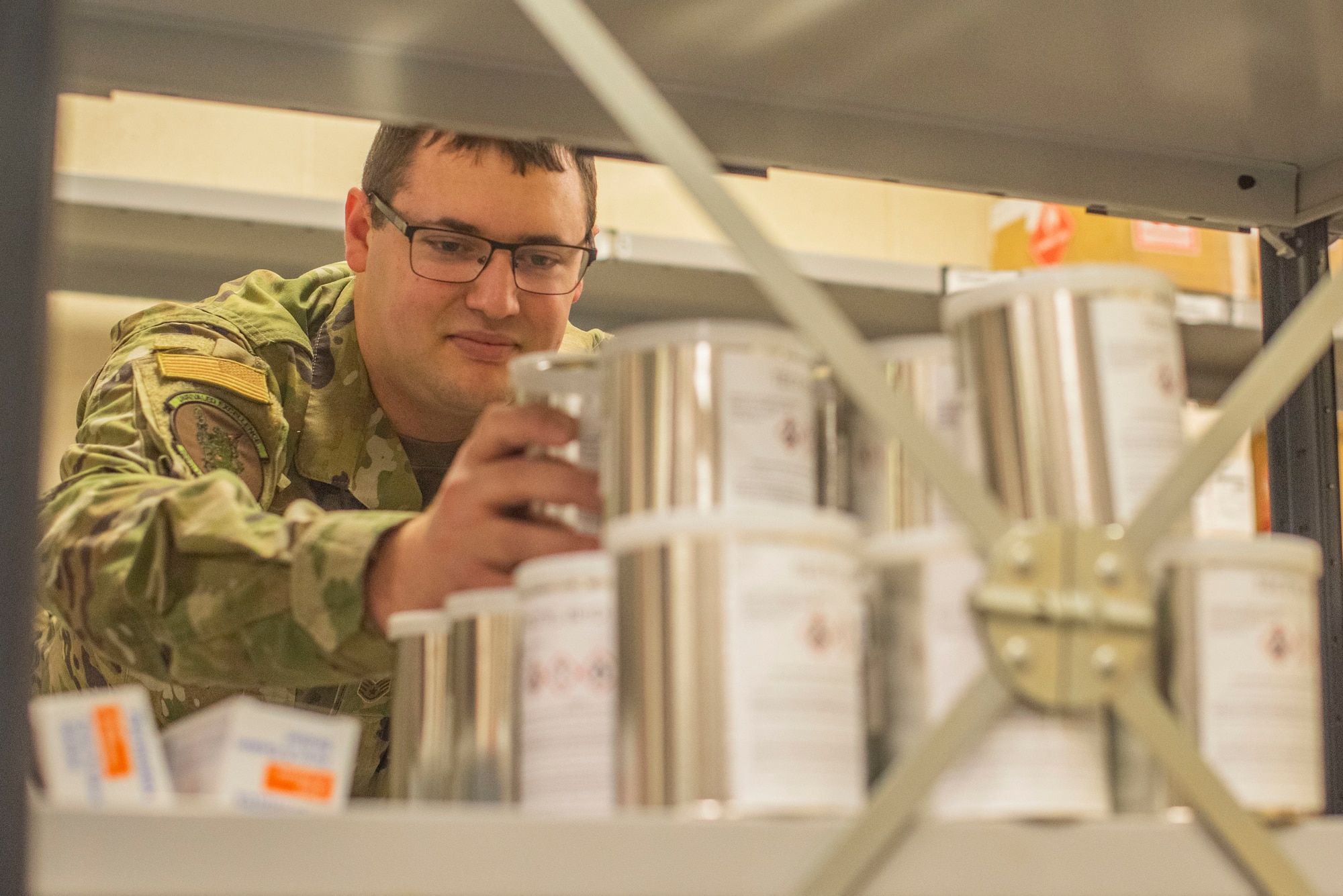 Staff Sergeant Nicholas Tendam, 100th Logistics Readiness Squadron assistant noncommissioned officer in charge of hazmart, stacks cans of corrosion prevention fluid Oct. 28, 2019, at RAF Mildenhall, England. Materials are separately stored at the hazmart pharmacy according to the hazard they present. (U.S. Air Force photo by Airman 1st Class Joseph Barron)