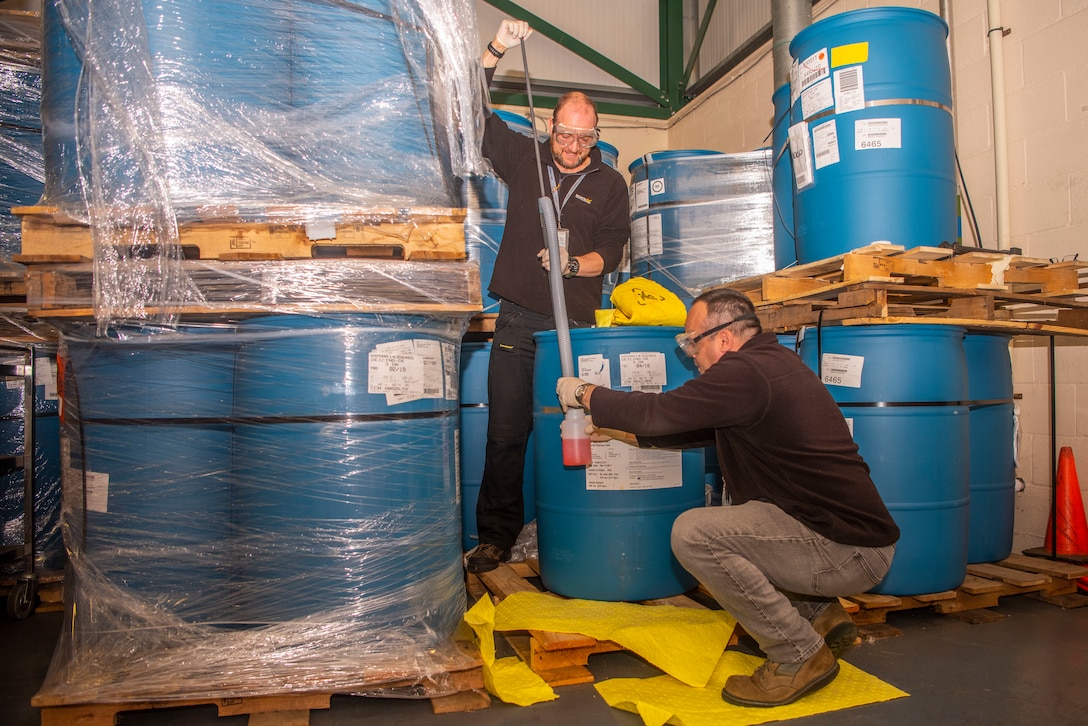 Michael Turner, standing, 100th Logistics Readiness Squadron hazmat technician, and Steven Hempstead, 100th LRS material handler, collect a sample of de-icing fluid Oct. 28, 2019, at RAF Mildenhall, England. Members of the hazmart pharmacy periodically determine the integrity of supplies they hold.  (U.S. Air Force photo by Airman 1st Class Joseph Barron)