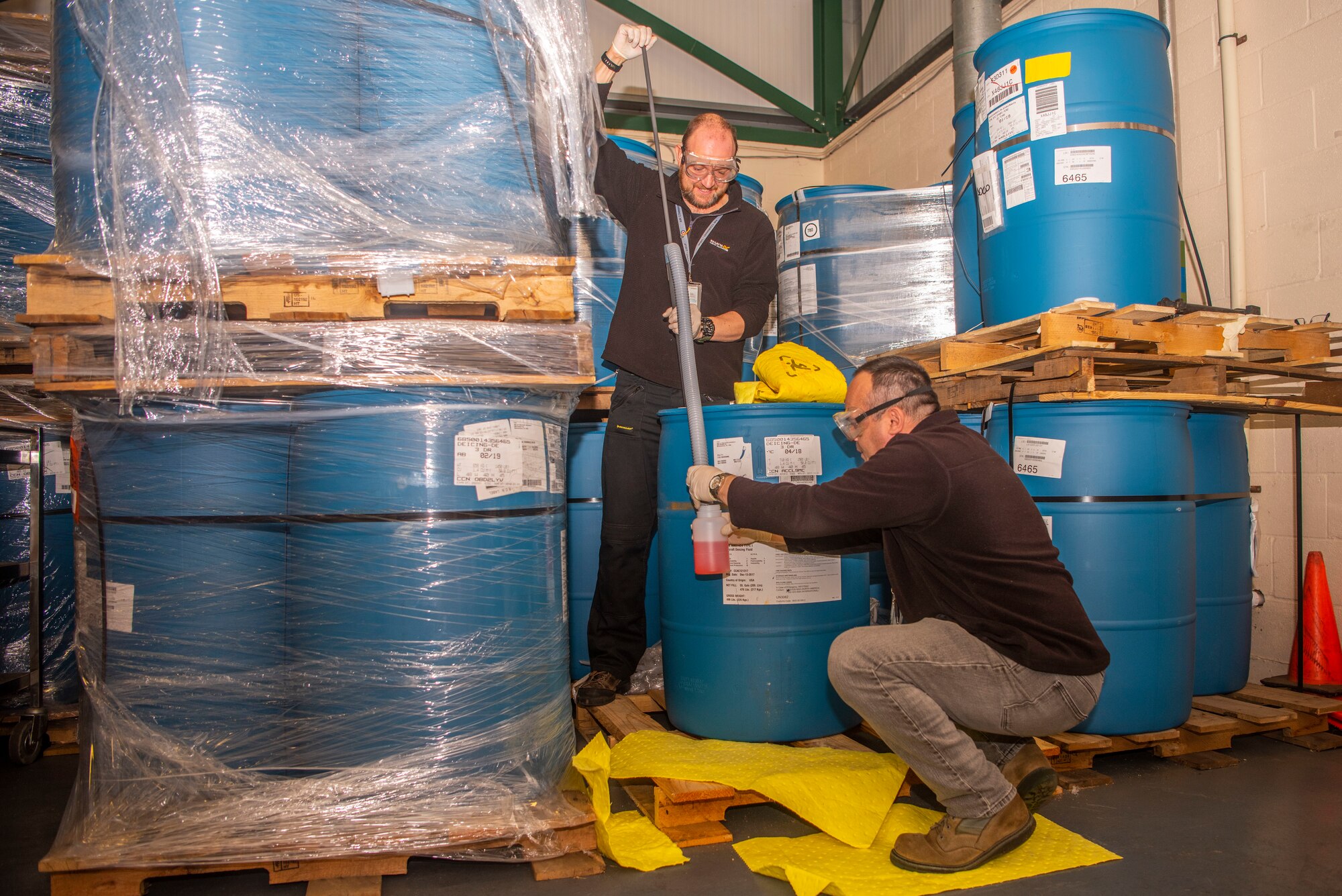 Michael Turner, standing, 100th Logistics Readiness Squadron hazmat technician, and Steven Hempstead, 100th LRS material handler, collect a sample of de-icing fluid Oct. 28, 2019, at RAF Mildenhall, England. Members of the hazmart pharmacy periodically determine the integrity of supplies they hold.  (U.S. Air Force photo by Airman 1st Class Joseph Barron)