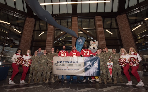 National Football League’s Kansas City Chiefs linemen and cheerleaders, members of Team Whiteman and USAA representatives pose for a photo with a Salute to Service banner that reads, "USAA Welcomes Our Ultimate Home Team. Military, Veterans and their Families."