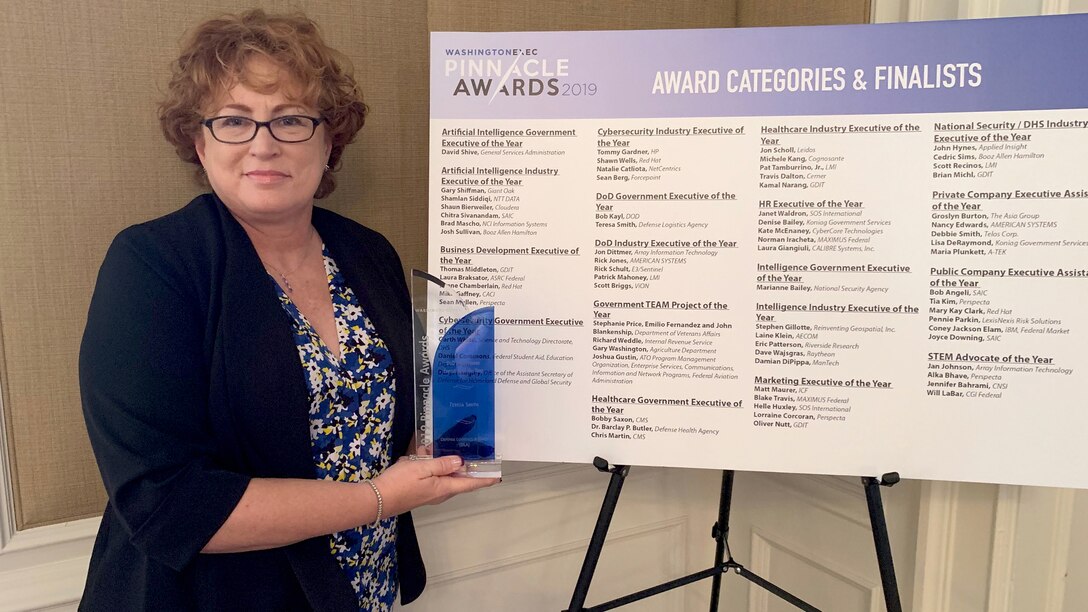 Teresa Smith holds her Department of Defense Government Executive of the Year in front of a sign listing other finalists