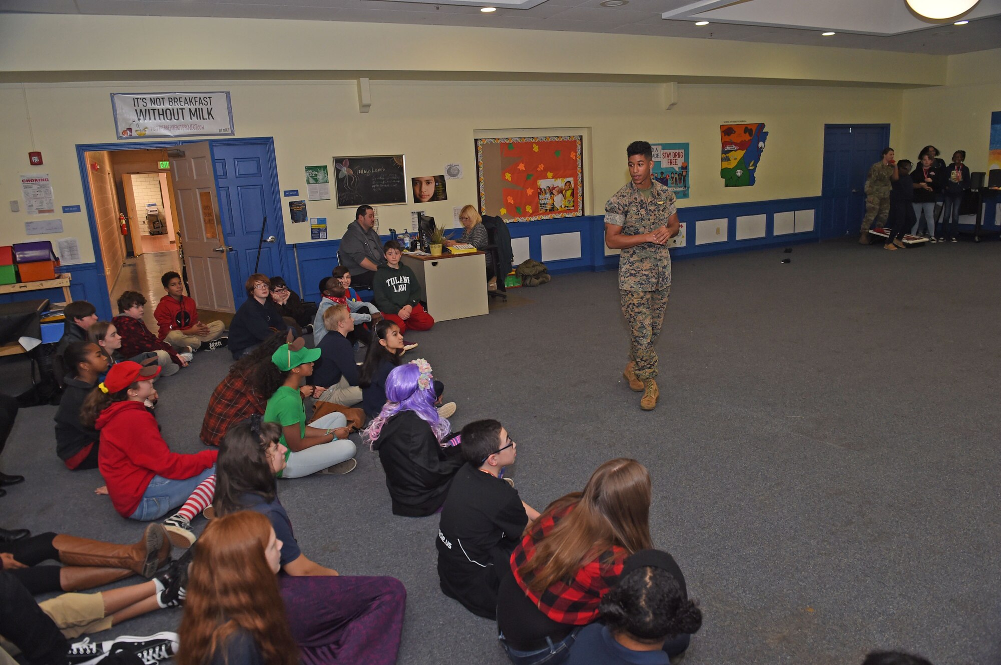 A Marine briefs children at a school assembly