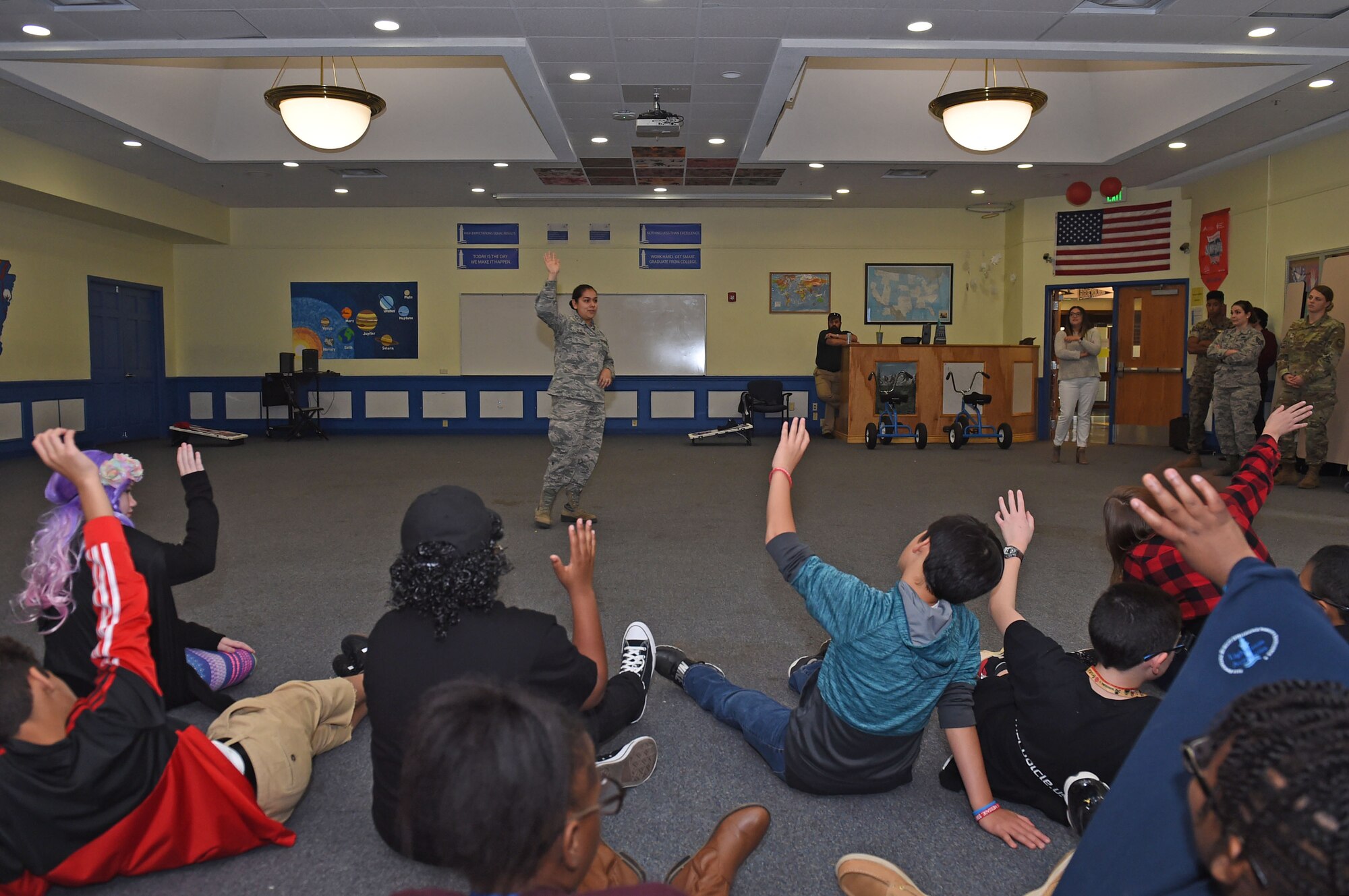 Children raise their hands during a red ribbon week assembly