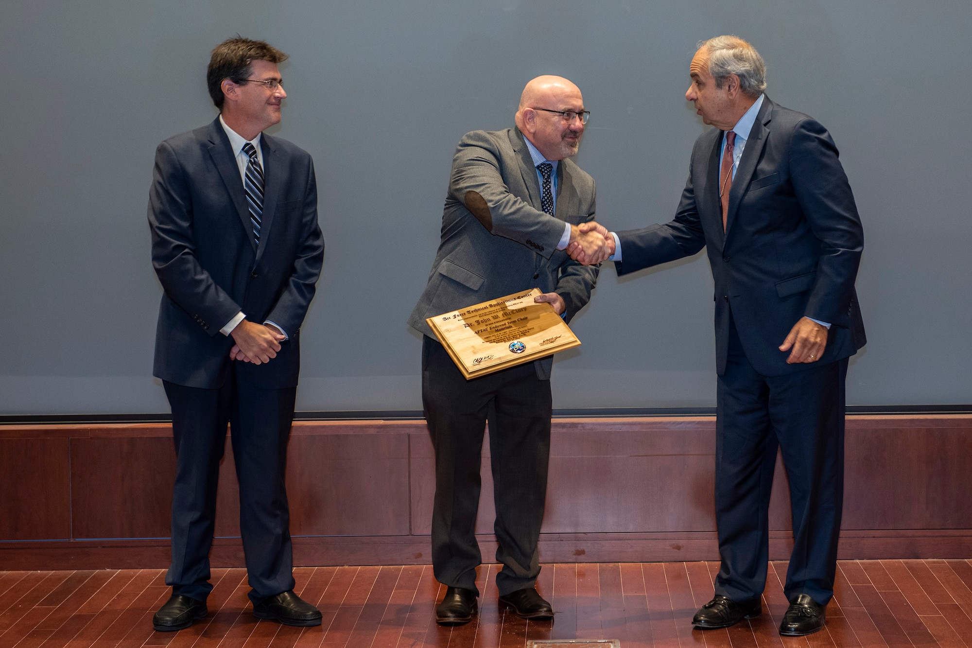 Dr. Richard J. Joseph (right), Chief Scientist of the U.S. Air Force, shakes the hand of Dr. John W. McClory, chairman of the Air Force Institute of Technology's Nuclear Engineering Program, after presenting him with the Endowed Term Chair Award during the Air Force Technical Applications Center's annual Research and Development Roadmap Forum Oct. 22, 2019.  Looking on is AFTAC's senior scientist, Dr. William Junek. (U.S. Air Force photo by Matthew S. Jurgens)