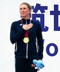 Air Force Reserve Maj. Judith Coyle stands at attention for the U.S. national anthem after receiving the gold medal for placing first in the women's senior division of the CISM Military World Games triathlon in Wuhan, China, Oct. 27, 2019. In her left hand she holds the mascot of the games, BingBing, presented to all medalists.