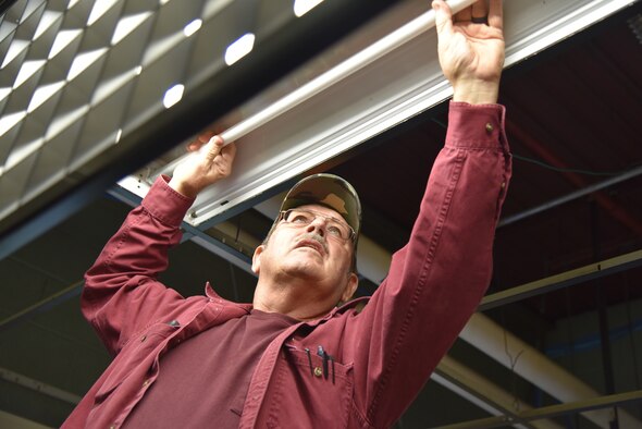 Man changes fluorescent light in ceiling