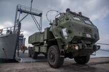 U.S. Marines with 12th Marine Regiment, 3rd Marine Division, and U.S. Soldiers with 97th Transportation Company, 10th Support Group, work together to quickly embark transportation vehicles and a High Mobility Artillery Rocket System on the U.S. Army Vessel Harpers Ferry (LCU-2022) during a joint service HIMARS embarkation training exercise in Kin, Okinawa, Japan, Oct. 31, 2019. This event marks the first time a Marine HIMARS was loaded on to an Army landing craft in the Indo-Pacific. Strategic mobility is key in the Indo-Pacific and the ability to transport the HIMARS over water is a vital capability that the 3rd Marine Division is now able to expand upon by partnering with the 10th Support Group. (U.S. Marine Corps photo by Lance Cpl. D’Angelo Yanez)