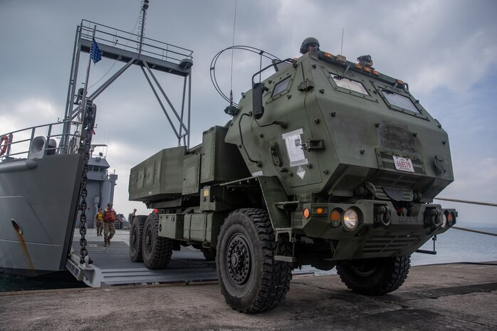 U.S. Marines with 12th Marine Regiment, 3rd Marine Division, and U.S. Soldiers with 97th Transportation Company, 10th Support Group, work together to quickly embark transportation vehicles and a High Mobility Artillery Rocket System on the U.S. Army Vessel Harpers Ferry (LCU-2022) during a joint service HIMARS embarkation training exercise in Kin, Okinawa, Japan, Oct. 31, 2019. This event marks the first time a Marine HIMARS was loaded on to an Army landing craft in the Indo-Pacific. Strategic mobility is key in the Indo-Pacific and the ability to transport the HIMARS over water is a vital capability that the 3rd Marine Division is now able to expand upon by partnering with the 10th Support Group. (U.S. Marine Corps photo by Lance Cpl. D’Angelo Yanez)