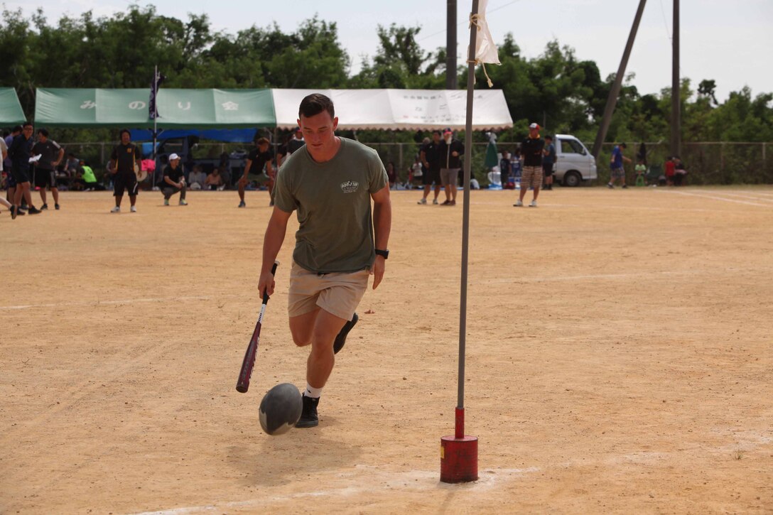 バットを使ってラグビーボールを転がす海兵隊員。沖縄県名護市辺野古区で11月3日（日）、第46回辺野古区民運動会が区民運動場で開催され、米海兵隊基地キャンプ・シュワブと沖縄防衛局も招待され、参加しました。