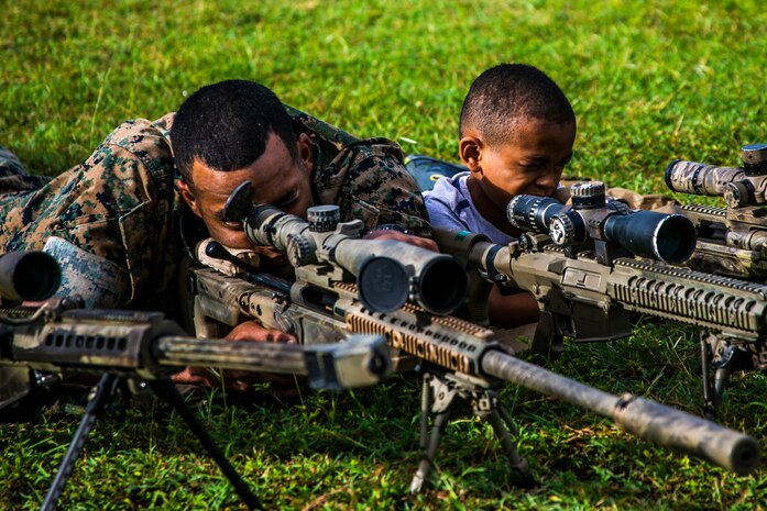 A U.S. Marine with 2nd Battalion, 3rd Marine Regiment, sights in on a sniper rifle with his son during the unit’s Island Warrior Spouse and Family Day on Marine Corps Base Hawaii, Oct. 29, 2019. The event gave Marines and Sailors the opportunity to create a positive community and give something back to the families that support the unit.