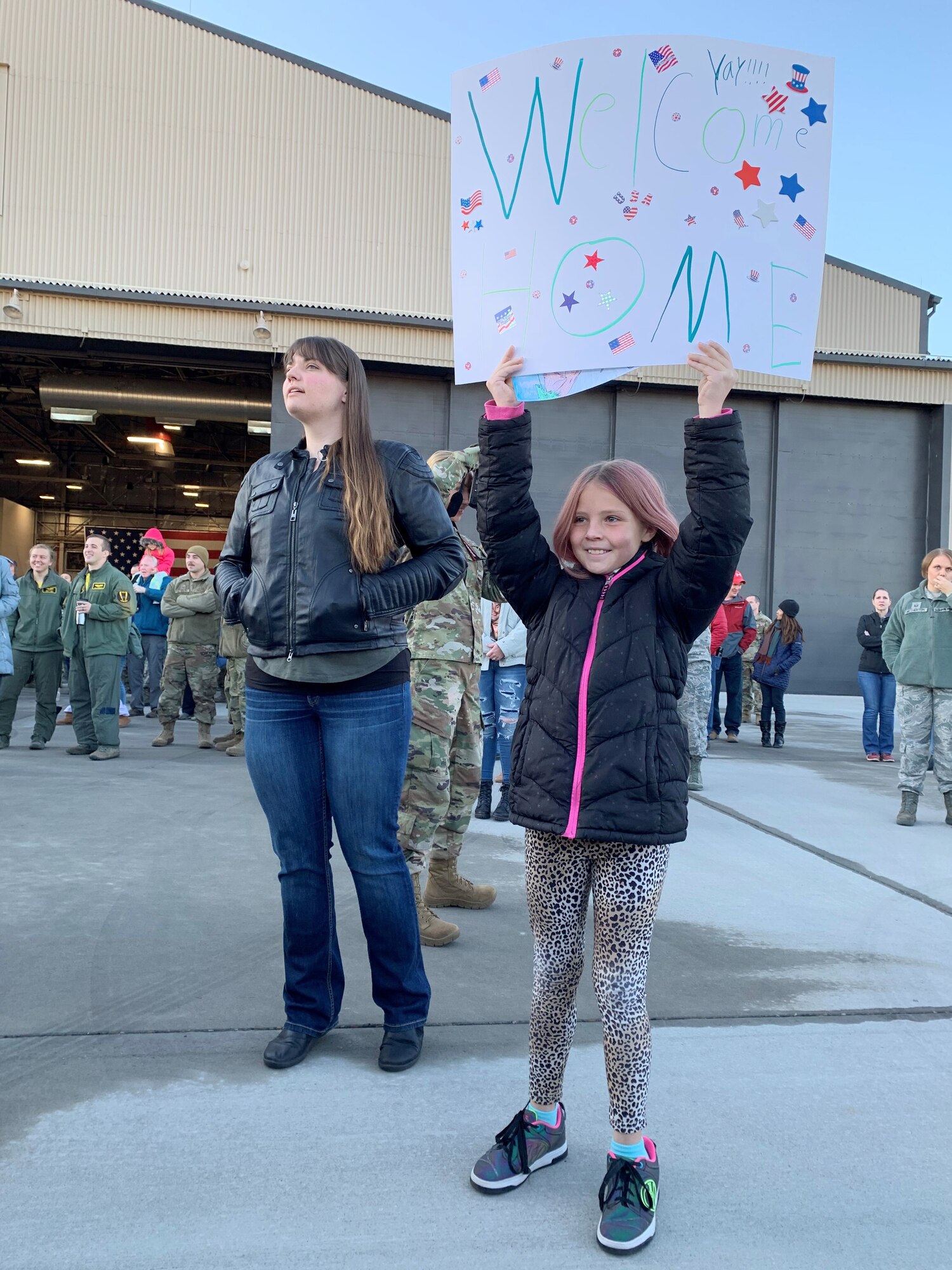 Liela Adamson, age 10, eagerly holds up her handmade “welcome home” sign while her mom, Kyleah Adamson, tries to get a glimpse of her boyfriend, Tech. Sgt. Logan Everton, who returned to Hill Air Force Base early Friday following a six-month deployment to Al Dhafra Air Base, United Arab Emirates