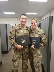 Kentucky National Guard Maj. Dayna Sanders (left) and National Guard Bureau Maj. Monica McGrath (right) receive their certification after completing the Phase 2 Cyber Operations Officer course.
