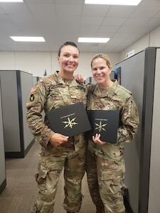 Kentucky National Guard Maj. Dayna Sanders (left) and National Guard Bureau Maj. Monica McGrath (right) receive their certification after completing the Phase 2 Cyber Operations Officer course.