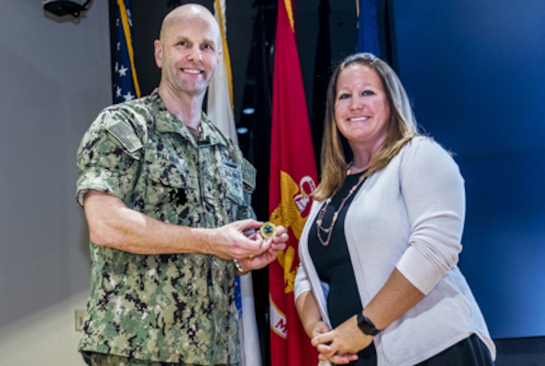 Two people pose with coin for camera.