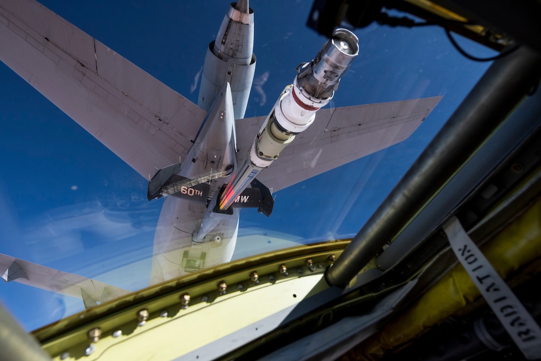 A military aircraft refuels another military aircraft in midair.