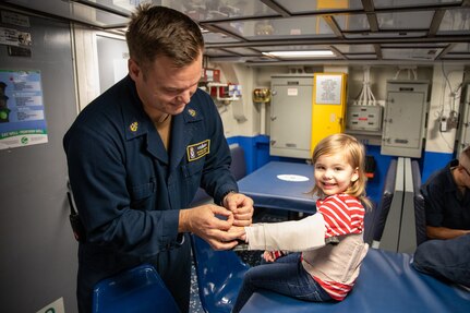 191101-N-AD347-0101 SASEBO, Japan (November 01, 2019) Chief Hospital Corpsman, Kenneth Van Tassel, bandges up his daughter for fun to show her what he does at work aboard Avenger-class mine countermeasures ship USS Pioneer (MCM 9). Pioneer, part of Mine Countermeasures Squadron 7, is operating in the 7th Fleet area of operations to enhance interoperability with partners and serve as a ready-response platform for contingency operations.