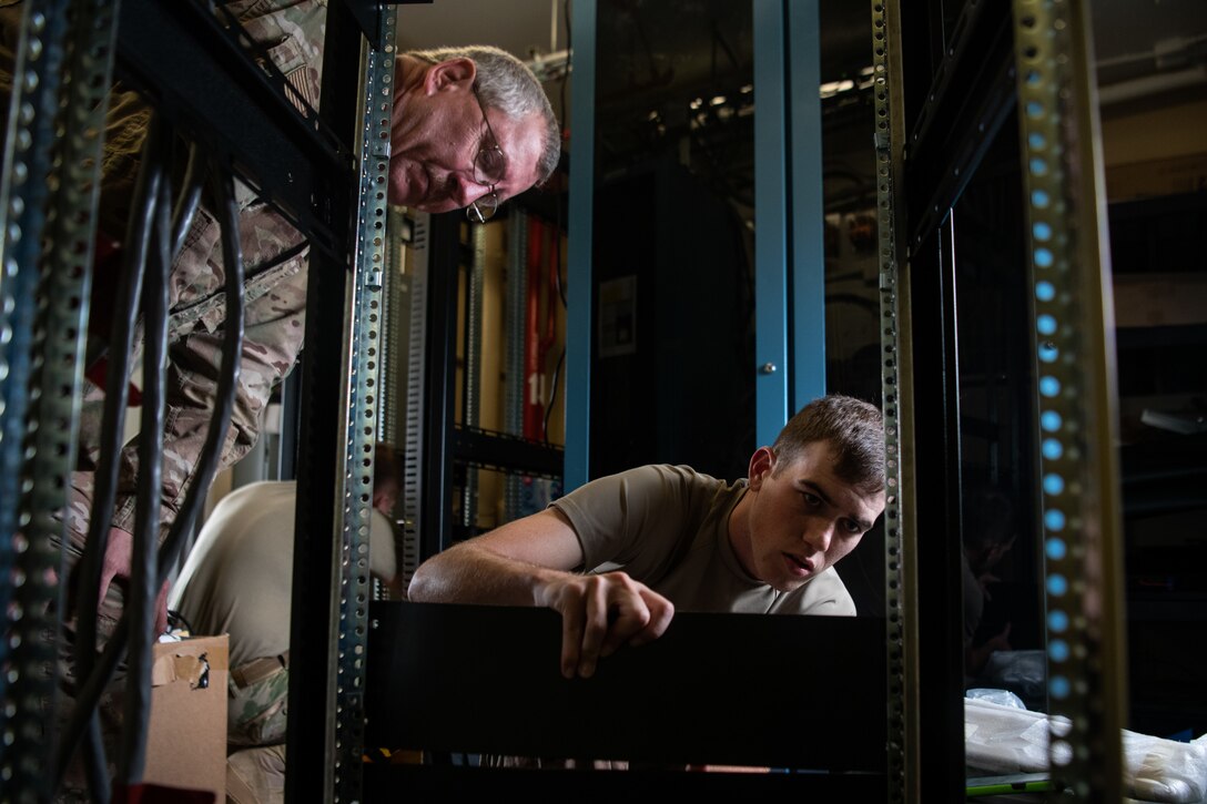 Senior Master Sgt. Charles Barkheimer, 205th Engineering and Installation Squadron quality assurance superintendent, watches as Senior Airman Tyler Nelson, 205th EIS cable antenna systems Airman, installs panels on a rack for radios in the air traffic control tower of the 36th Operations Support Squadron at Andersen Air Force Base in Guam on Sept. 15, 2019. The 205th EIS had seven Airmen working to install ten CM-300/350 radios in the 36th Operations Support Squadron air traffic control tower in Guam as part of the U.S. Air Force Air Traffic Control and Landing Systems Radio Replacement Program. (U.S. Air National Guard photo by Staff Sgt. Brigette Waltermire)