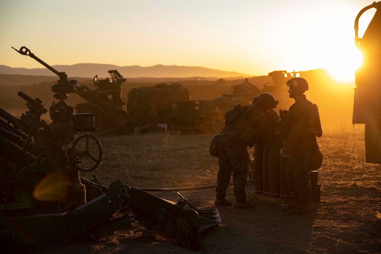 Artillery and Marines gather at dusk in the field