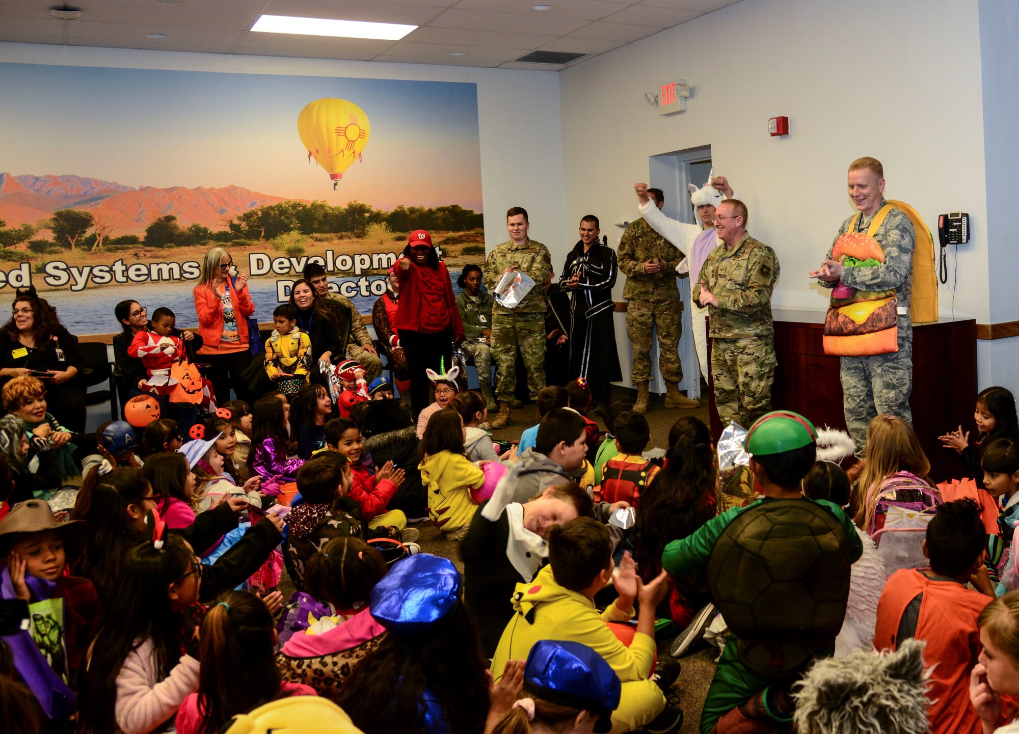 Kirtland Elementary School students and teachers listen to a briefing from members of the Space and Missiles Systems Center (SMC) on Kirtland Air Force Base, N.M., Oct. 31, 2019. Each year, SMC invites the school to their Haunted Halloween event in which the entire building is filled with spooky decorations and hundreds of pounds of candy are passed out to costumed visitors.